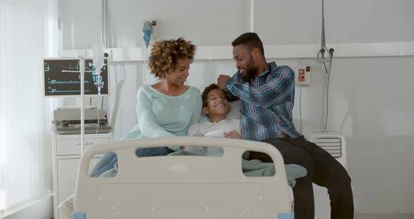 Afroamerican Parents Visit Sick Son at Hospital Ward