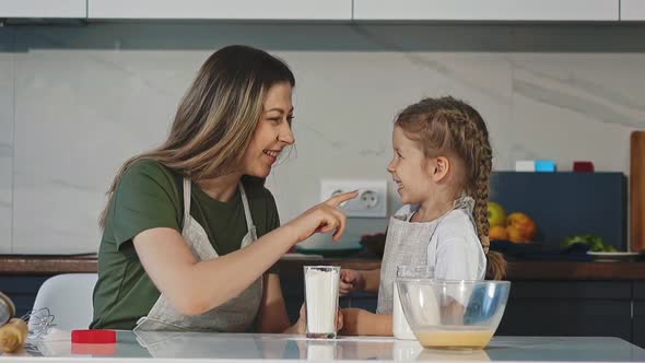 Mother and Girl Touch Noses By Fingers with Flour at Table