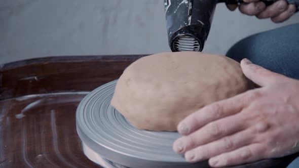 Professional Male Potter Drying Clay with Special Dryer In Pottery Studio