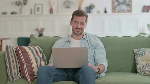 Young Man Doing Video Call on Laptop on Sofa