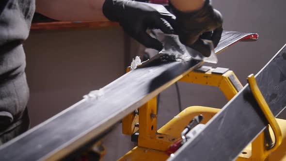 Ski Maintenance and Repair Concept. Workshop Worker Doing Waxing and Repairs Ski and Snowboard