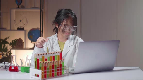 Asian Scientist Girl With Dirty Face Mixes Chemicals In Test Tube And Work With Laptop Computer