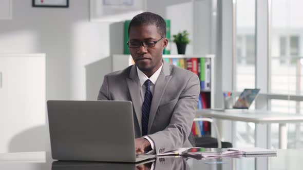 Portrait of Successful AfricanAmerican Politician Working on Laptop in Modern White Workspace