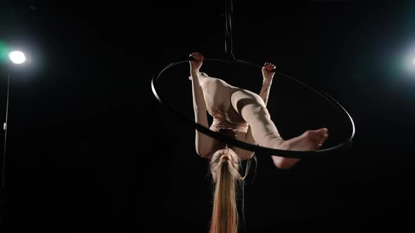 Slim Aerial Gymnast in Split Hanging on Air Hoop Spinning in Slow Motion at Black Background with