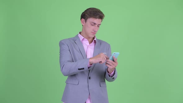 Happy Young Businessman Thinking While Using Phone