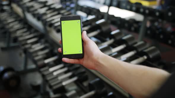 Male Hand with Smartphone in Gym Fitness Application Results Green Screen