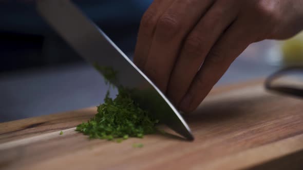 Chef chopping herbs on a wooden board.