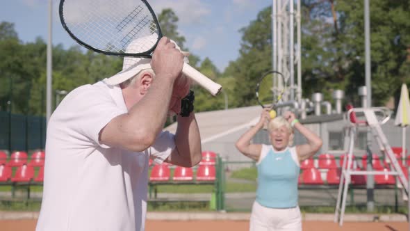 The Upset Mature Couple Lost the Tournament on the Tennis Court. Senior Man and Woman