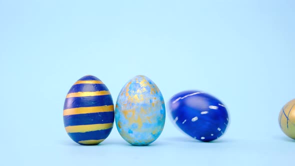 Easter Eggs are Rolling Knocking Each Other on Blue Table