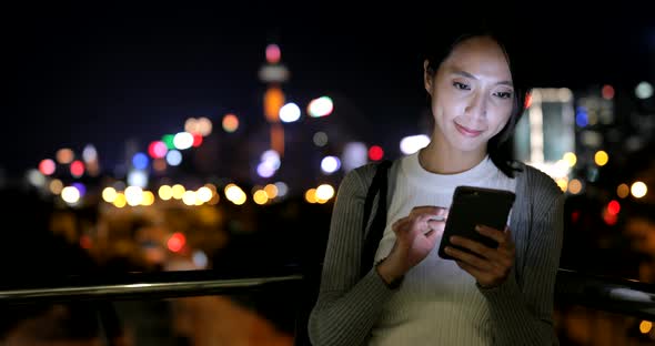 Woman using cellphone in city at night 