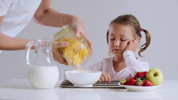 Sleepy Girl Is Starting To Eat Her Cornflakes with Milk for Breakfast.