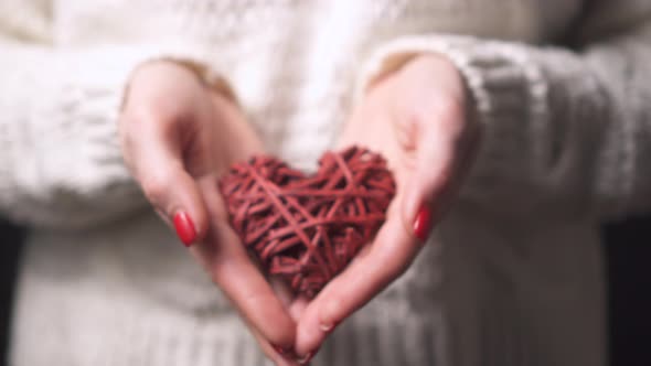 Close-up Female Hands Hold a Decorative Heart, Selective Focus.