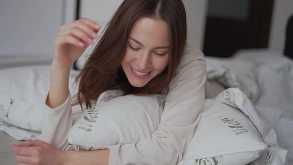 Delighted Female Hugging Pillow on Bed