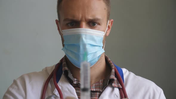 Portrait of Doctor in Protective Mask Pouring Liquid From Syringe and Tapping on It