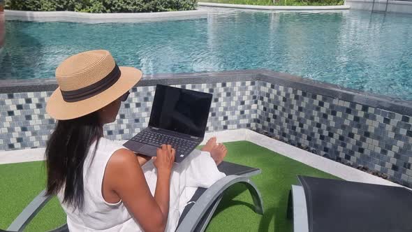 Asian Women with Hat Checking Laptop on Holiday Vacation Digital Nomad Concept