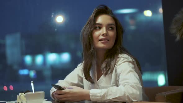 Girl Uses a Smartphone While Sitting in a Cafe Alone