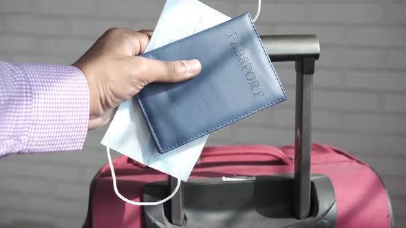 Holding Passport in Hand with Suitcase on Ground