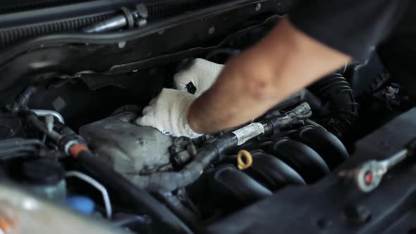 Male Auto Mechanic Changes Spark Plugs in a Car Engine