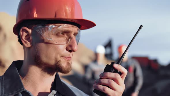 Skilled Male Construction Engineer in Uniform Reporting Using Walkie Talkie During Working Closeup