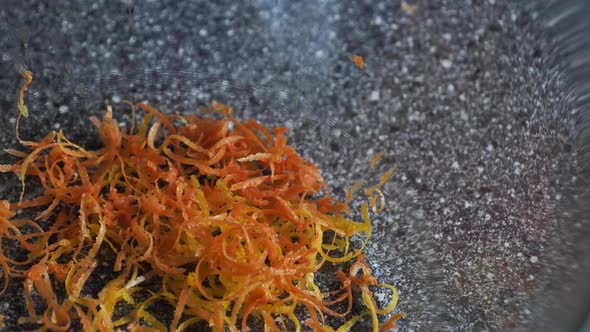 Grated orange grapefruit peel falls into a bowl