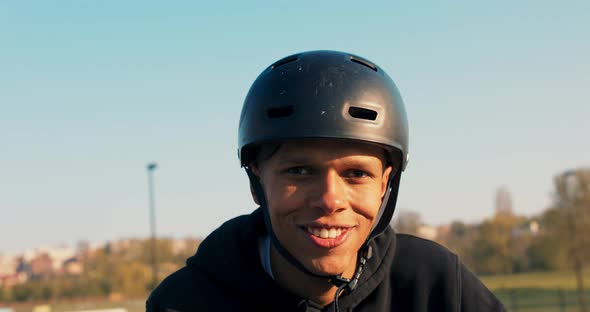 A Teenager in a Black Sweatshirt and Helmet Stands on a Ramp at a Skatepark