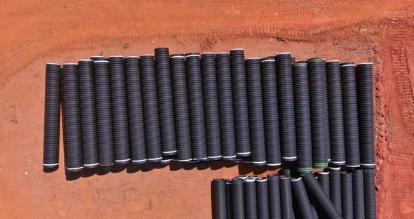 New Black Plastic Pipe with a PVC Seal Stacked in Rows at the Construction Site for a Drain System