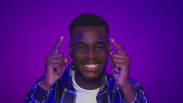 Black Guy Pointing Fingers At His Head Over Purple Background