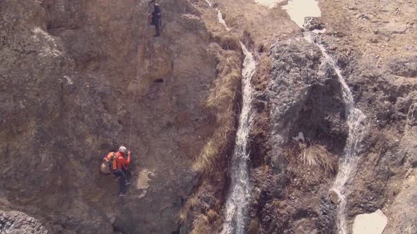 Aerial view of men rock climbing up a waterfall