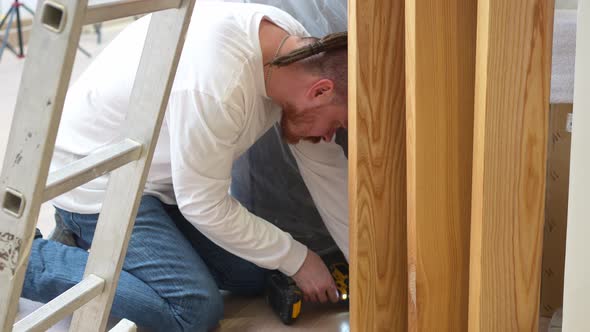 the Carpenter Screws with a Screwdriver Wooden Ash Lamellae to the Floor