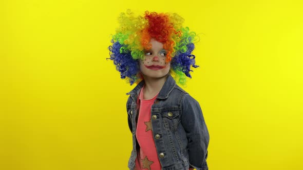 Little Child Girl Clown in Rainbow Wig Angry Standing and Waiting for Something. Halloween