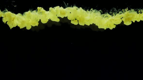 Slow Motion Yellow Ink Drops in Water and Mixes Swirling Softly Underwater