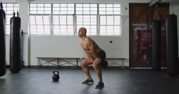 Fit caucasian man working out with kettle bell at the gym