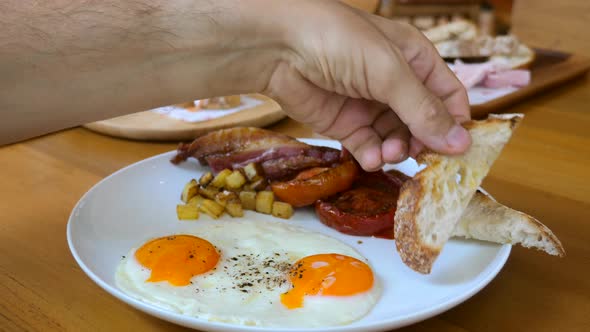 Man Hand Dip Toasted Bread in Fried Egg Yolk in Restaurant on Breakfast or Lunch