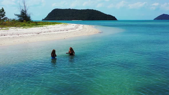 Women relaxing on paradise resort beach vacation by blue ocean and white sandy background of Thailan