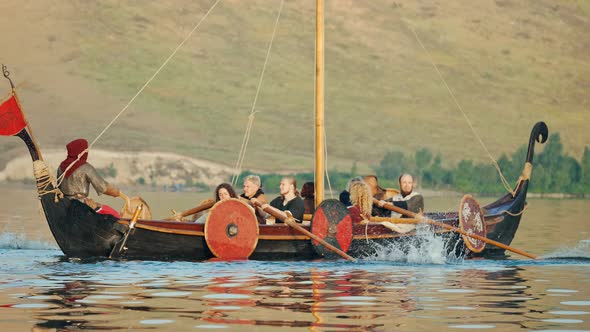 Vikings Row on Drakkar in the Middle of the River