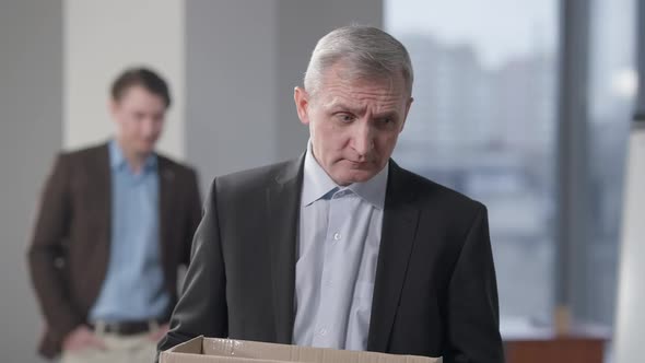 Portrait of Fired Stressed Senior Man Holding Box Standing in Office