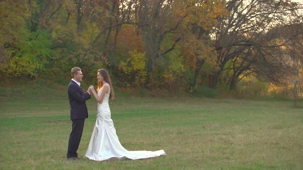 Happy Newlyweds Enjoy Each Other on Sunny Day in Autumn Park. Man Kisses the Hands of His Beloved