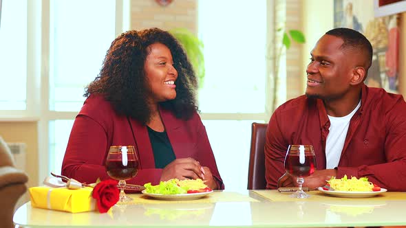 African American Couple in Love Drinking Wine From Glasses and Eating Italian Pasta in Living Room