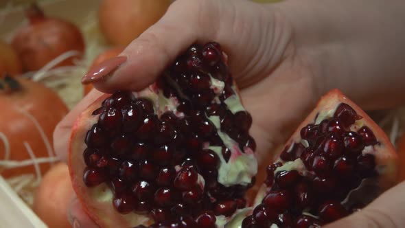 Female Hands are Breaking a Juicy Ripe Pomegranate Into the Six Pieces