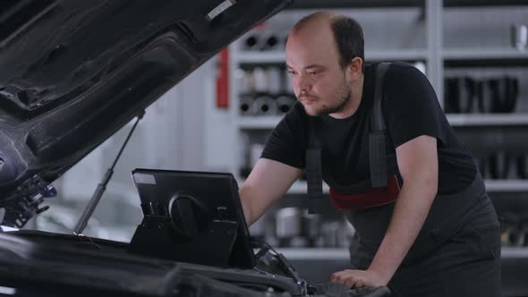 Male Mechanic Uses a Tablet Computer with an Augmented Reality Diagnostics Software