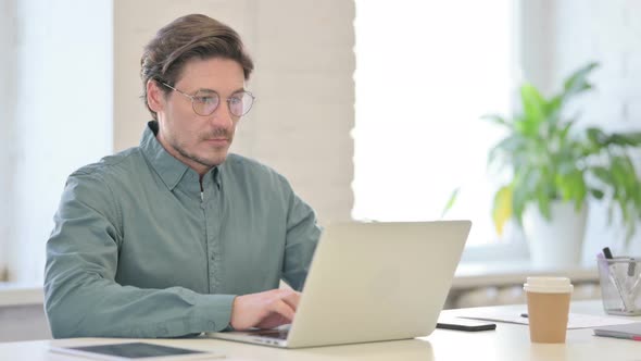 Middle Aged Man Working on Laptop in Office