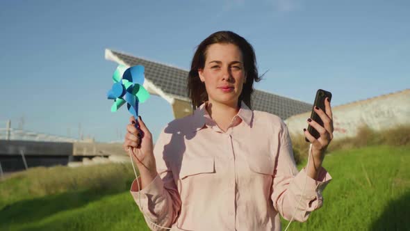 Slow motion shot of young woman with pinwheel and smartphone