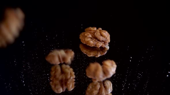 Walnut kernels fall on a black mirror surface