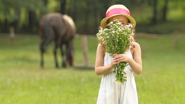 Child with Wild Flowers in Their Hands Sniffs Them. Slow Motion