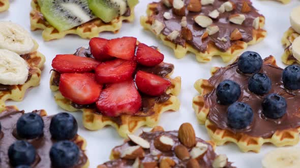 Rotating Background of Appetizing Sweet Wafers with Chocolate Spread Nuts and Fruits on a White