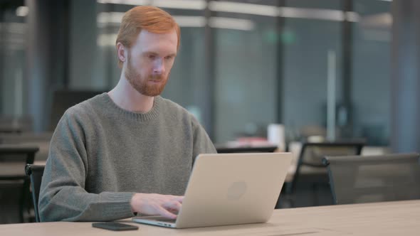 Young Man Working on Laptop in Office