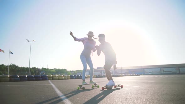 Young Attractive Mixed Race Couple Riding Skateboards and Having Fun Slow Motion