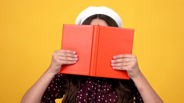 Smart Schoolgirl in Glasses Hiding Behind Hard Cover Notebook for Reading and Studying Literature