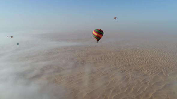 Aerial view of hot-air-balloon flying in the clouds on desert in Dubai, U.A.E.