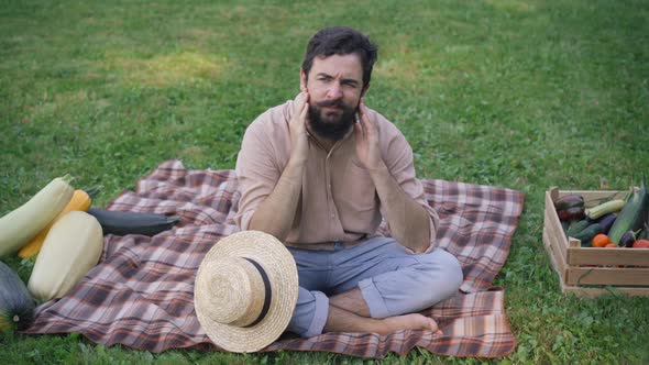 Wide Shot of Exhausted Man Taking Off Straw Hat Holding Head in Hands Rubbing Temples